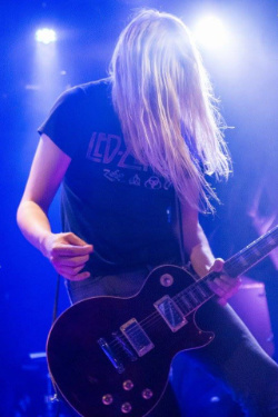 docent Jelle wuift met zijn blonde haren terwijl hij op een gitaar ramt